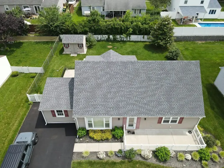 Aerial view of a suburban house with a gray roof surrounded by trees