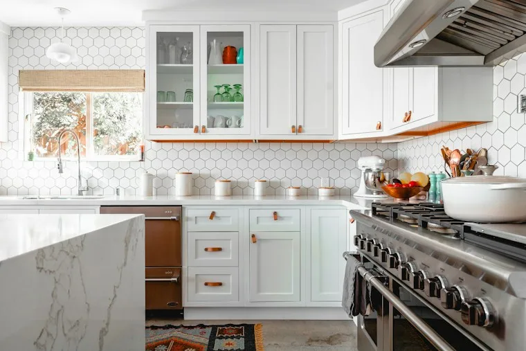 Bright kitchen with white cabinets, hex wall tiles and a marble island, like many Cary homes