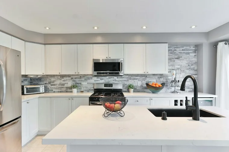 Built-in stainless steel wall oven and microwave stacked in kitchen cabinets