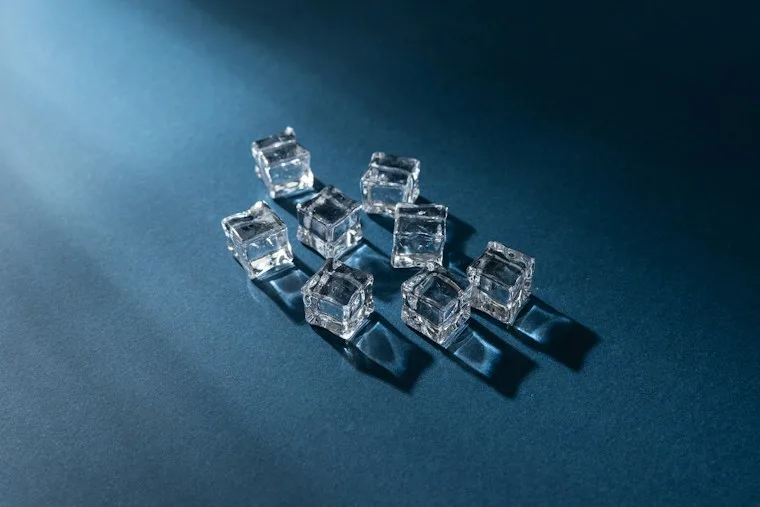 Clear ice cubes scattered on a blue surface