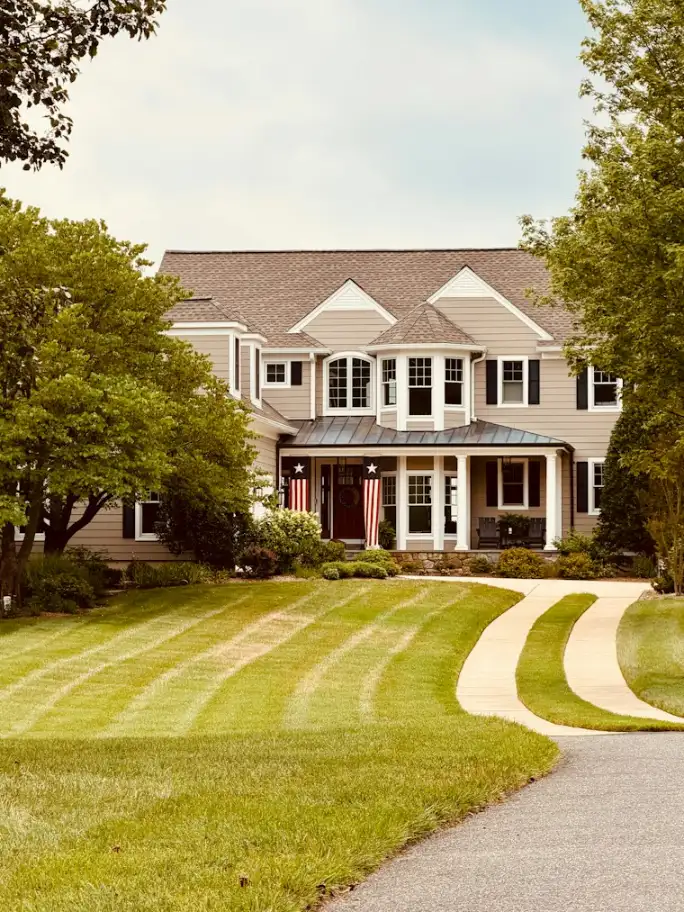 Large home with a long winding driveway and a neat green lawn
