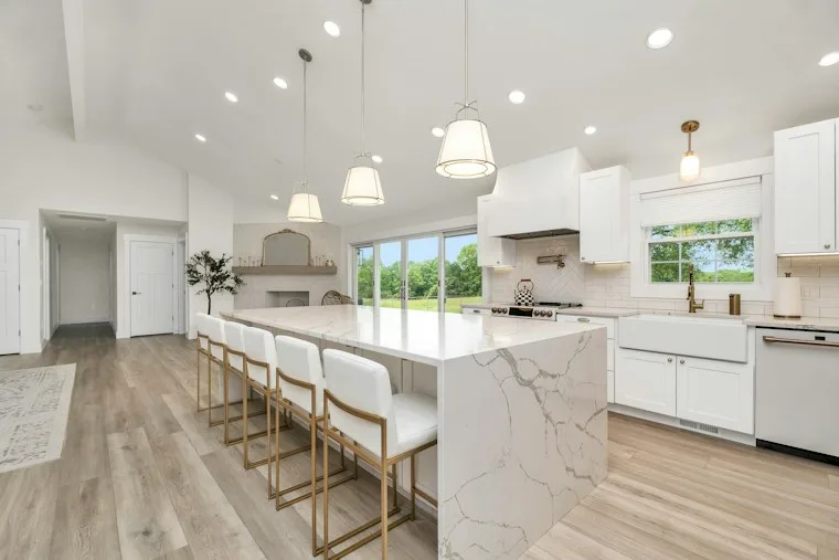 Large kitchen with a marble island, white cabinets and built-in appliances
