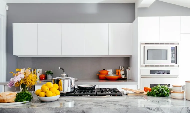 Modern white kitchen with a large marble island and built-in appliances