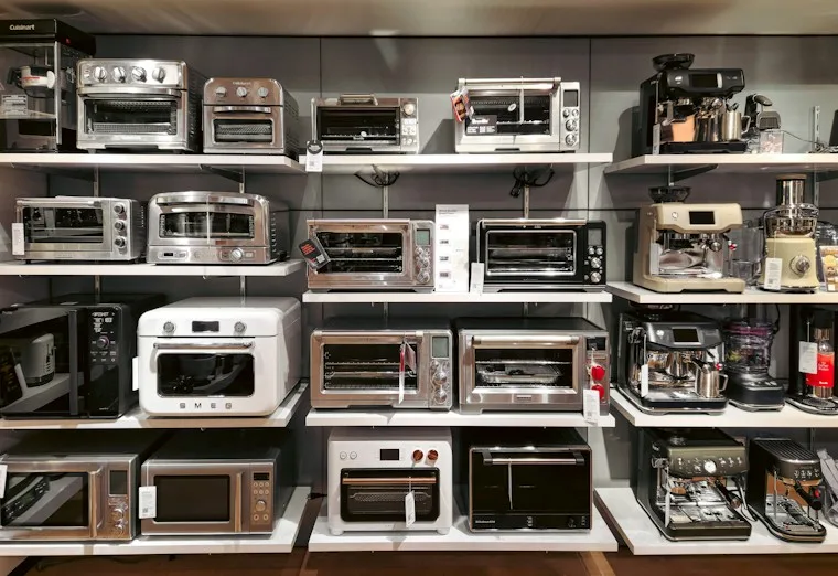 Several new microwave ovens lined up on a store shelf