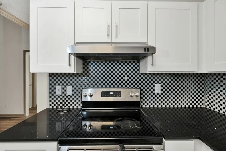 Silver and black gas range with four burners and an oven below