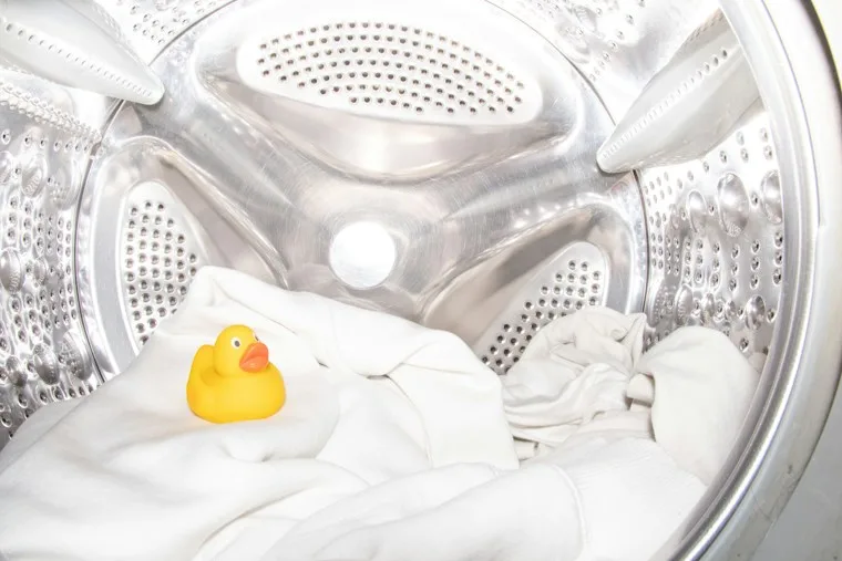 Small toy duck sitting inside the drum of a washing machine
