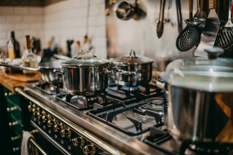 Stainless steel cooking pots on a gas cooktop with blue flames