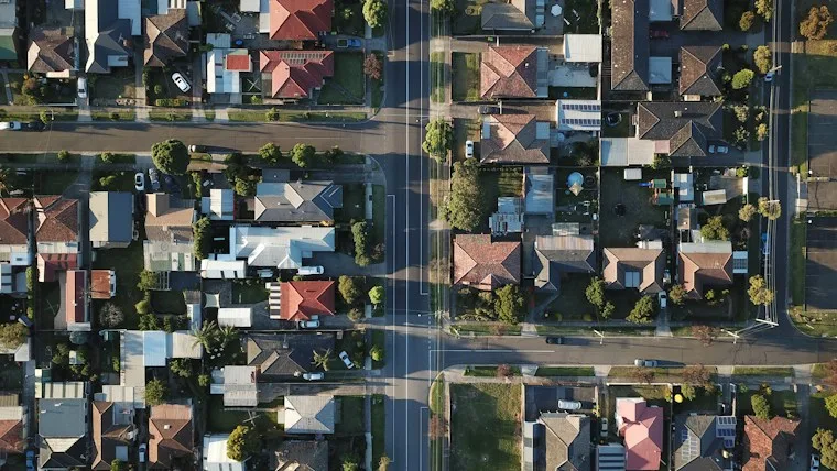 Top-down view of a suburban neighborhood with rows of homes and green trees