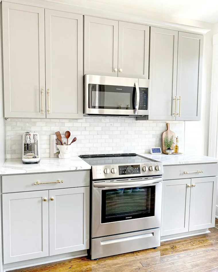 White microwave oven sitting on a white wooden kitchen cabinet